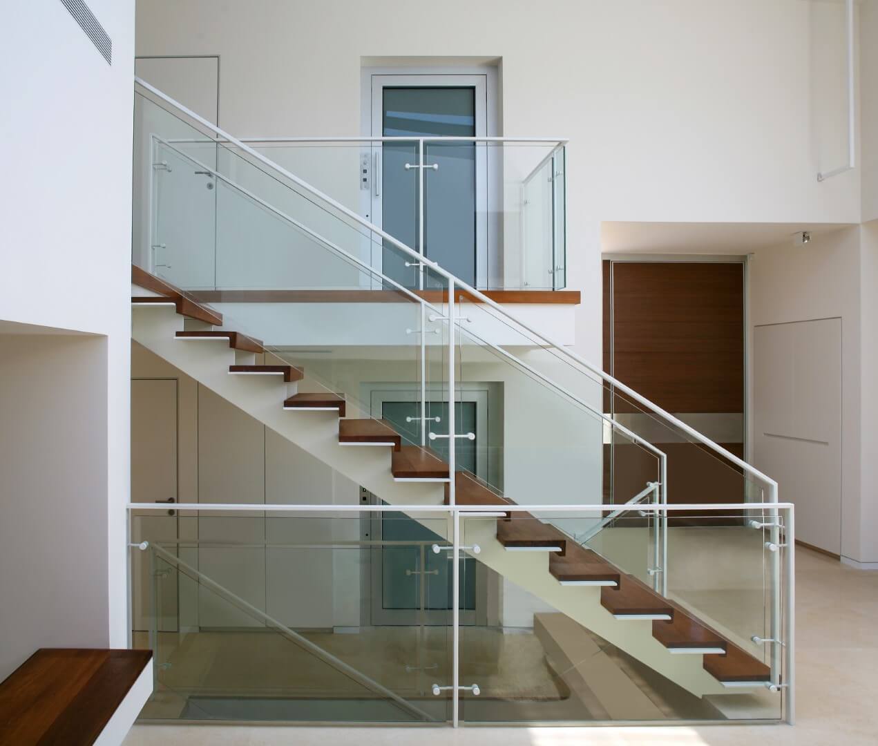 מדרגות קונסטרוקציות ברזל לבן עם מדרכי ברזל ועץ עץ טיק בשילוב של זכוכית שקופה ומאחז יד מברזל