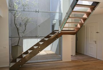 מבט על שני גרמי מדרגות מרחפות מברזל, קורטן ועץ אלון אמריקאי מולבן עם מעקה זכוכית המחברות בין שתי קומות הבית
