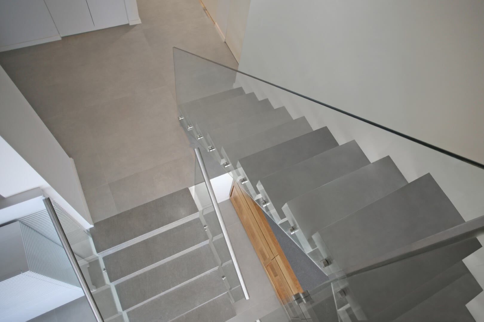 מבט על על שני גרמי מדרגות מרחפות משיש עם מעקה זכוכית שקוף