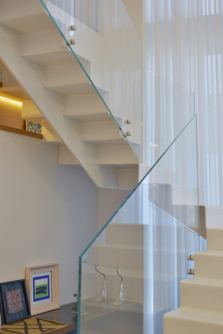 פוקוס על מעקה הזכוכית שמלווה את שלושת גרמי מדרגות הברזל שעולות למעלה אל הקומה השניה