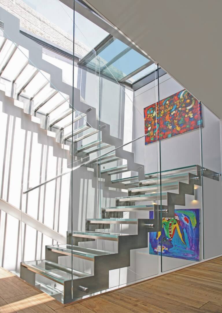 מבט על שני גרמי מדרגות נירוסטה וזכוכית מבעד למעקה הזכוכית שמגיע עד לגובה התקרה