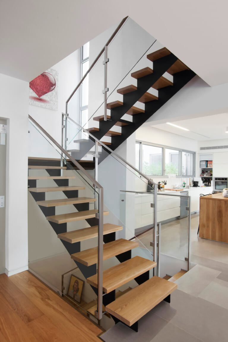 שני גרמי מדרגות ברזל שחור עם מדרגות עץ אלון אמריקאי ומעקה זכוכית בסמוך למטבח