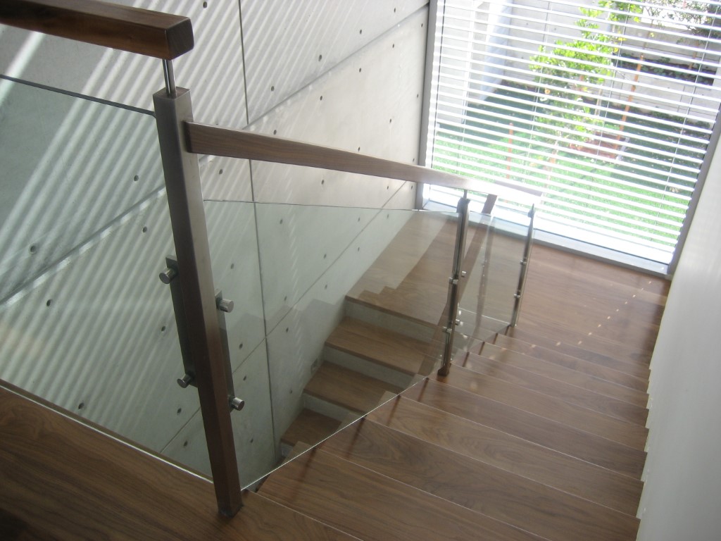 מדרגות עץ בהיר משולבות עם מעקה זכוכית וידיות עץ