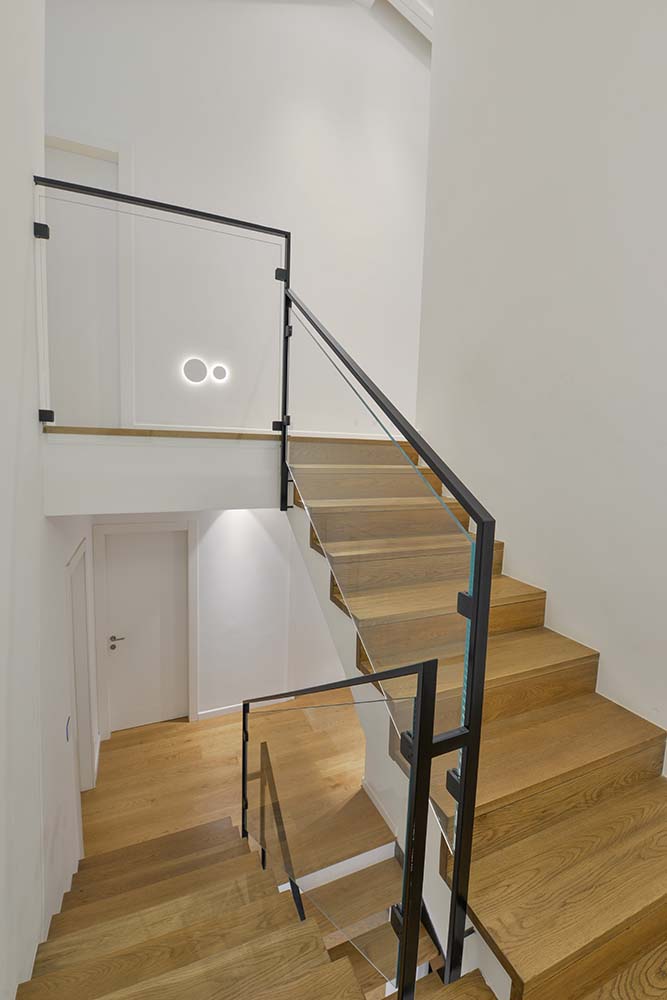 שני גרמי מדרגות עץ אלון אמריקאי ומעקה ברזל שחור עם זכוכית שקופה בוילה בתל אביב