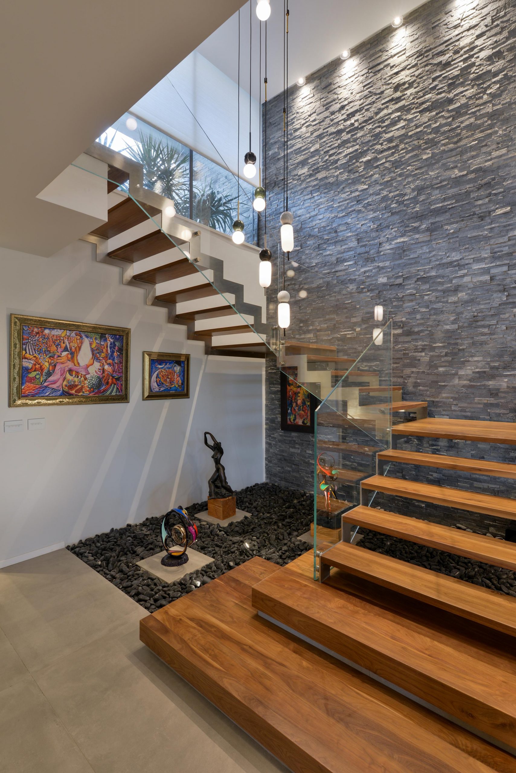 מדרגות עץ אגוז אמריקאי עולות לקומה השניה על קונסטרוקציות מנירוסטה ולצידן מעקה זכוכית אקסטרה קליר בוילה ברמלה
