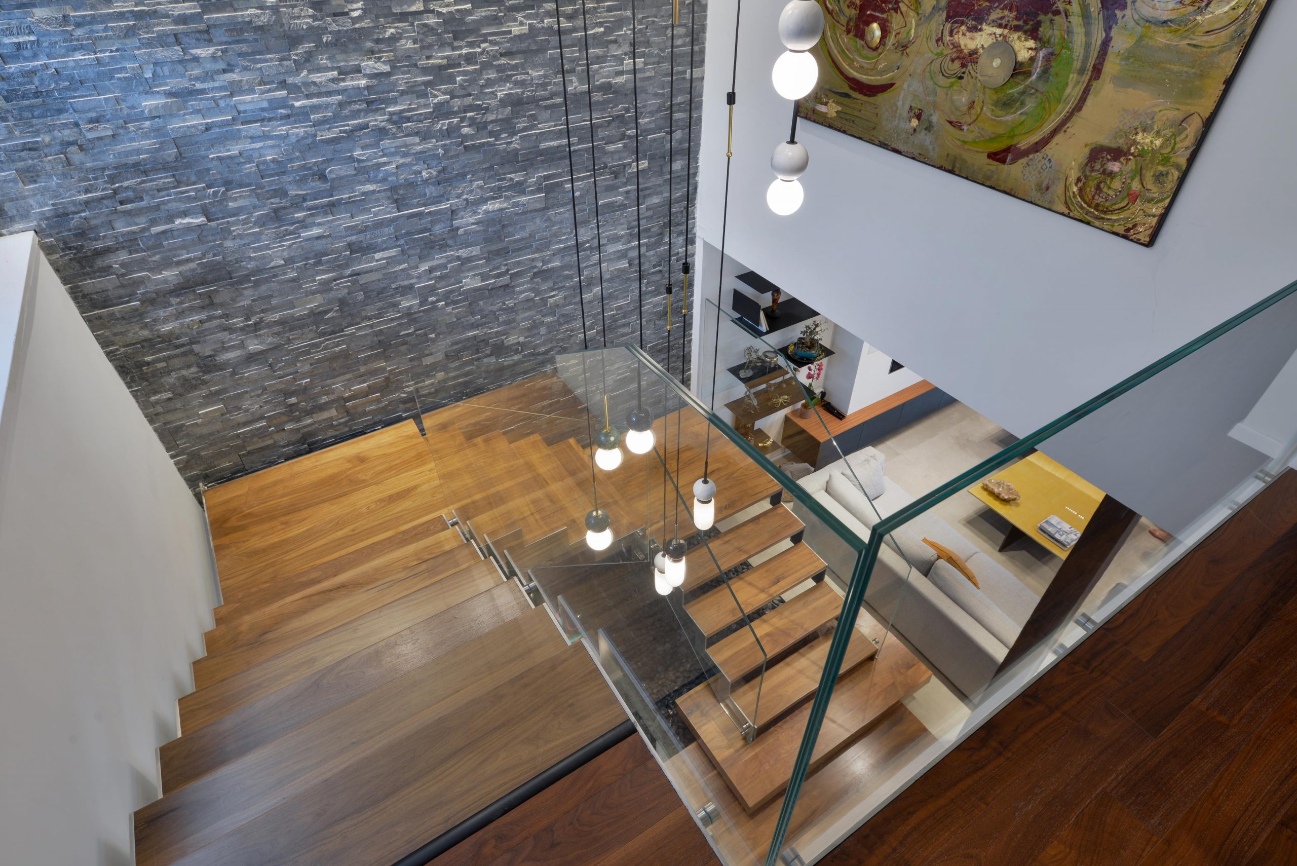 מבט מלמעלה על מדרגות עץ אגוז אמריקאי על קונסטרוקציות מנירוסטה ולצידן מעקה זכוכית אקסטרה קליר בוילה ברמלה